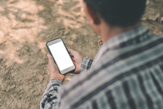 Asian Farmer Working On A Mobile Phone With A Blank Screen In His Garden