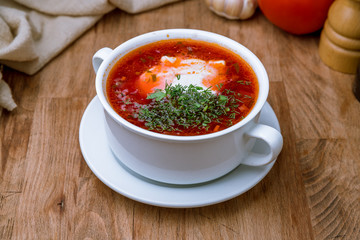 Borscht with sour cream on wooden table