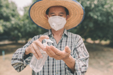 Fototapeta premium Asian farmer man wears a mask and is washing their hands with alcohol gel to prevent the coronary virus outbreak (COVIT-19) and bacteria. Corona Virus Concept