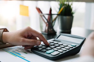 Close up hand of  accountant or banker working on calculator to calculate financial data report,...