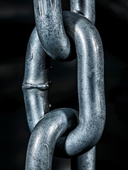 One chain link. Links of a metal chain close-up on a dark background.