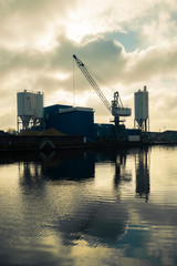 Obraz premium Silhouette of mortar and cement industry construction with large crane along a river