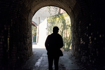 Light at the end of the tunnel. Silhouette of people in an underground passage