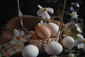 many easter eggs in a basket with flowers on a black background