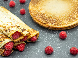 crepes filled with raspberry jam and fresh raspberry on black slate