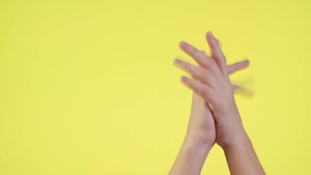 Woman hands keeping fingers crossed, waiting for special moment, making wish pray isolated over yellow background in studio.