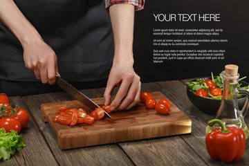 Woman cooking fresh healthy salad. Female hands cutting vegetables on board on wooden table with sample text.