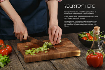 Woman cooking fresh healthy salad. Female hands cutting vegetables on board on wooden table with sample text.