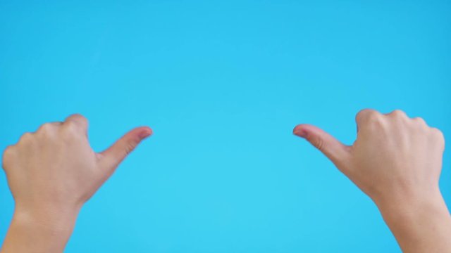 Woman hands pointing on copyspace and showing thumbs up over blue background