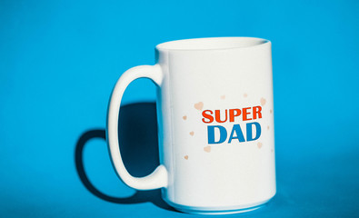 The mug that says "Super Dad". White mug on blue background. Mug. Dad's Day.