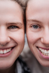 Extreme close up portrait of the faces of two young girls with clear eyes. Caucasian girls laughing
