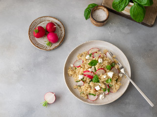 healthy salad with quinoa, fresh radish, feta cheese and basil in a ceramic plate on a gray background. Superfood meal. horizontal image. place for text. top view.