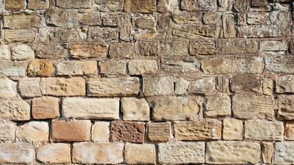 old yellow and brown sandstone wall made of blocks of irregular shape  background