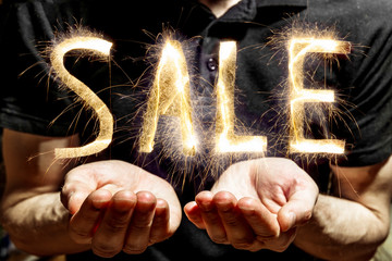  man holds a sparkling sale sign on a dark background