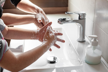 Mother teaching her daughter how to properly wash their hands with soap to prevent coronavirus - obrazy, fototapety, plakaty