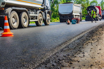 Close up background of a new road and paving machine on it that was recently paved with builders in...