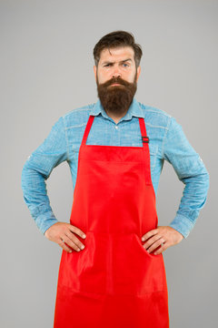 Bearded Chef Or Waiter Wearing Red Apron. Brutal Waiter Or Barista. Barber Man In An Apron With Long Beard. Handsome Confident Guy Master. Entrepreneur In His Modern Look