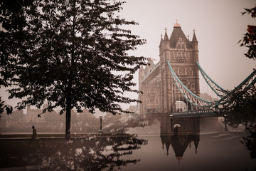Rainy and foggy day at Tower Bridge, London. The bridge is reflected in a mirror in the lower half of the photo.