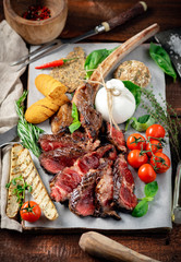 Tomahawk grilled steak cut into pieces with vegetables on a wooden Board, cooking meat barbecue