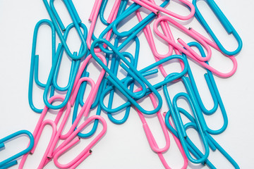 Pink and blue paper clips on a white background, scattered