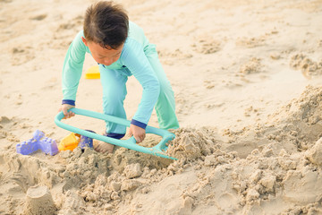 Fototapeta na wymiar Boy play sand with toy on beach alone