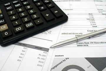 Calculator lying on the table with pen and documents with figures for accountants