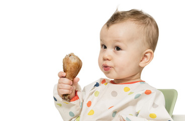 Portrait of hungry baby boy with fried chicken leg in his hand on white isolated background.