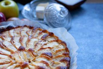 Baked apple pie tart with some ingredients like sugar, floor, apples, butter. Closeup. Dark Food....