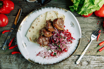 Restaurant dish on a wooden background. Azerbaijani shish kebab and grilled ribs.