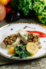 Restaurant dish with vegetable decor on a wooden background. Sea fish fried on a plate with sauce.