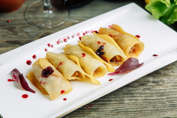  Restaurant dish on a wooden background with vegetables. Stuffed cabbage with meat and sauce on a plate.