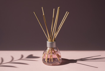 Aromatic reed air freshener on pink background hard shadow. Aromatherapy sticks. Air refresher...