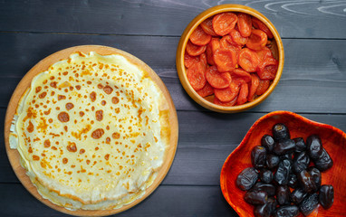 Dried apricots pancakes and dates on a wooden background