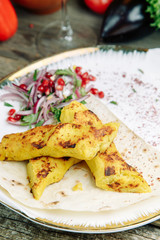  Restaurant dish on a wooden background with vegetables. Vegetarian Lula kebab made of mashed potatoes with onions on pita bread.