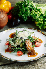  Restaurant dish on a wooden background with vegetables. Salad with beef tenderloin and arugula on a plate.