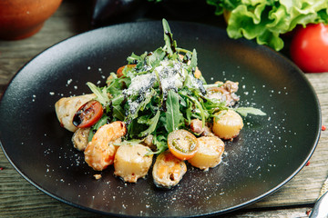  Restaurant dish on a wooden background with vegetables. Salad with shrimp, avocado and arugula on a plate.