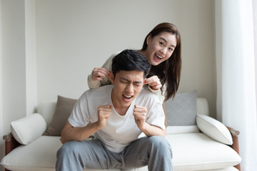 A young Asian couple taking pictures of each other on the sofa