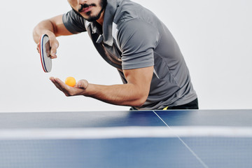Cropped image of bearded ping pong player serving ball in the beginning of game
