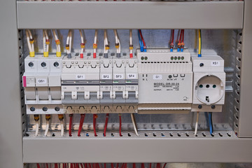 Fuse holder, two circuit breakers, power supply and socket in the electrical Cabinet. The wires and cables are connected to the electrical equipment and laid in the cable channel.