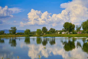 landscape with lake, trees and blue sky with clouds