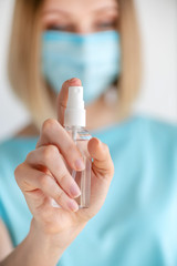 Female doctor or nurse in uniform puts a disinfectant spray on her hands. Disinfection and hand washing
