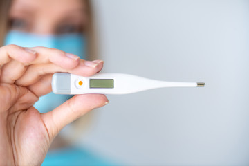 Female doctor or nurse holds a electronic thermometer for measuring temperature
