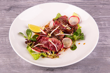 Warm beef salad with terriaki sauce, served with radish, lime and fresh salad