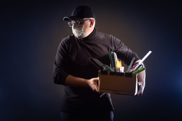 An unemployed man with a mask on his face and a box of office supplies. Unemployment. Job loss due to the coronavirus epidemic. Ruin. Bankruptcy. Depression from job loss.