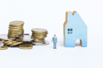 Miniature business man with stack of coins and wooden blue house isolate on white background, finance and banking business, insurance or house loan