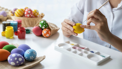 Obraz na płótnie Canvas Happy Asian woman painting eggs for Eastertime at home. Family preparing for Easter.