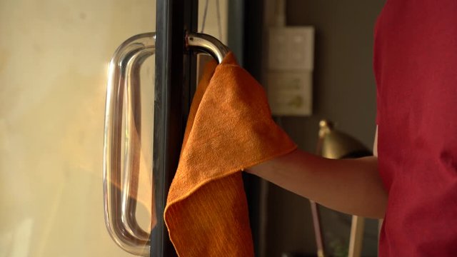 Close-up of human hands using alcohol sanitizer to clean a door knob of public business shop to avoid Coronavirus inflection spread through droplets. Corona Virus (Covid 19) disease protection.