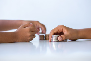 Children's hands putting money coins to a stack of coins on the table
concept: Saving money wealth and financial Personal, finance management  loan for a home,
diagram chart earnings to plan profit
