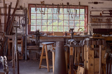 large table by the window Old vintage craftsman's workshop blacksmith with a jaw vise and other tools