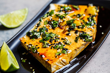 Tofu with marinade of soy sauce, ginger, spices and sesame seeds in black plate.